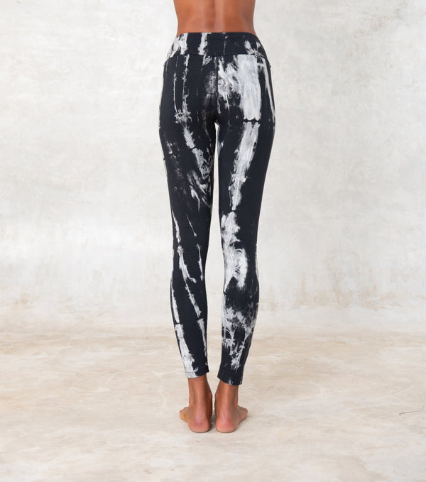women wearing low waist black and white tie-dye leggings. The leggings are ankle lenght and mae of organic cotton.