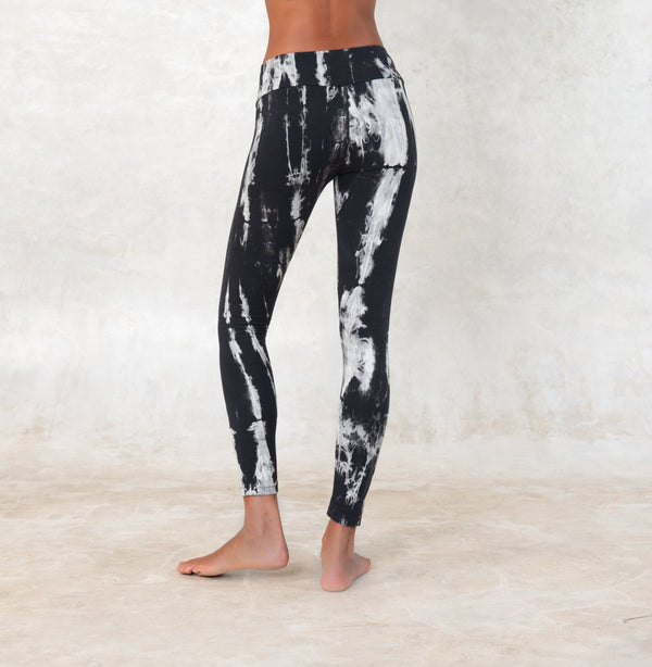women wearing low waist black and white tie-dye leggings. The leggings are ankle lenght and mae of organic cotton.