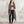 Load image into Gallery viewer, A woman stands barefoot against a textured light gray wall, wearing a long open-front gray cardigan over a gray sports bra and black leggings.
